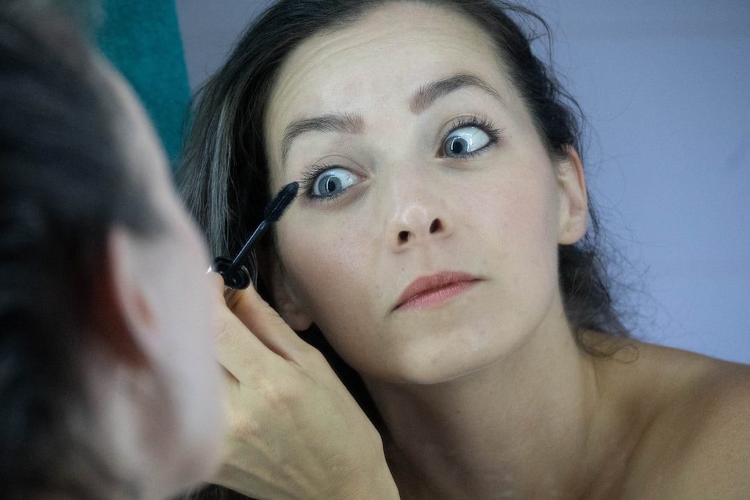 a woman is putting mascara on her face