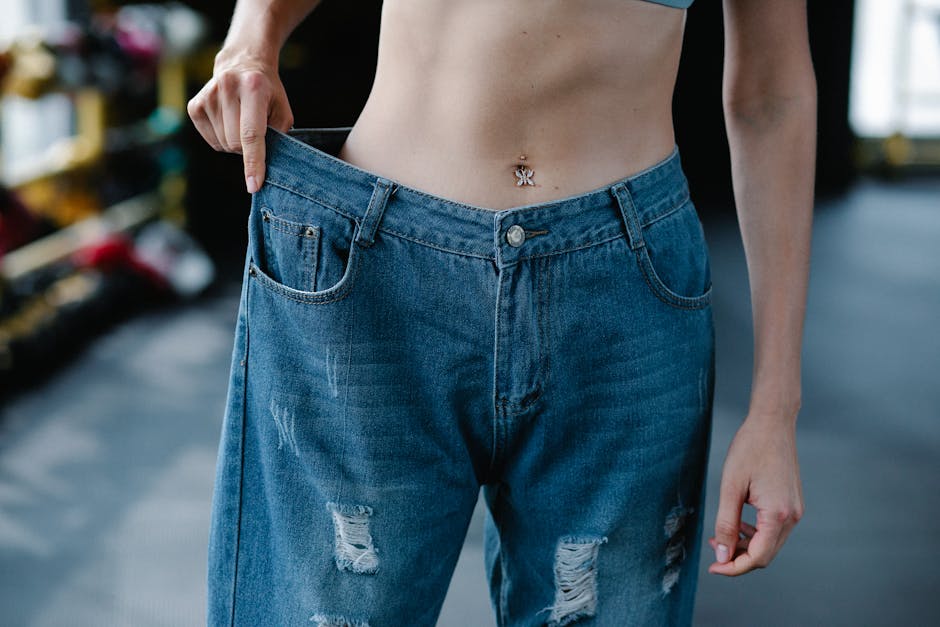 A woman showcases significant weight loss results confidently wearing loose jeans.